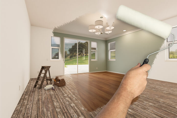 Man using a roller to paint the walls of a home after Home Renovation Technician Training.