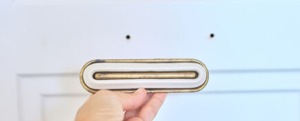 Cabinet making training grad holding a golden cabinet door handle.