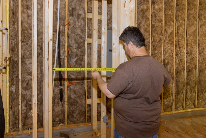 A male electrician measuring his work area after electrician training