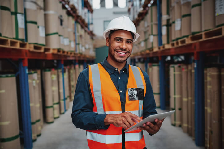 logistics training grad holding a tablet standing in warehouse