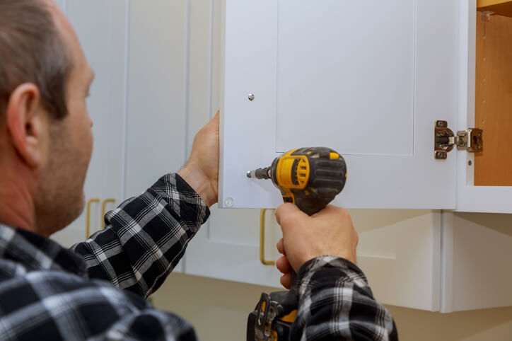 A cabinet maker putting screws in a kitchen cabinet after cabinet making training