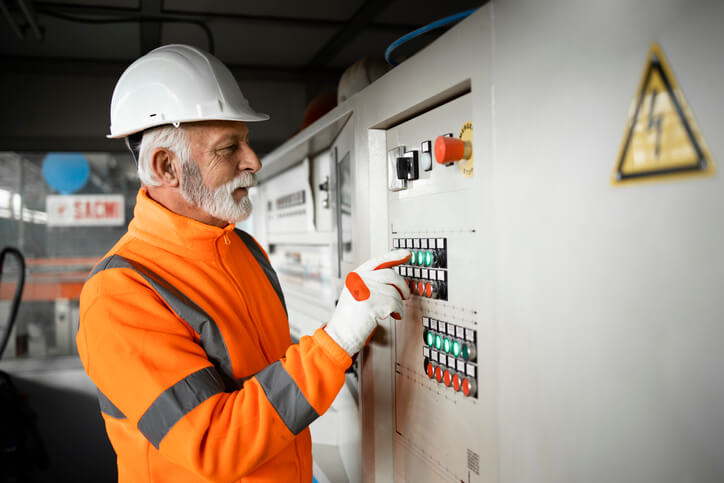 A male electrical foreman checking electric installations at a factory after electrician training