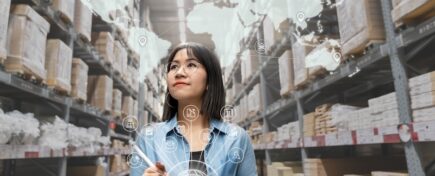 Portrait of a young Asian supply chain management woman looking at inventory in a warehouse using a smart tablet.