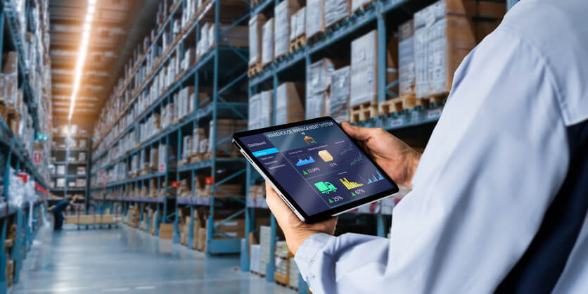 A logistics professional operating inventory management software in a warehouse after completing his logistics training